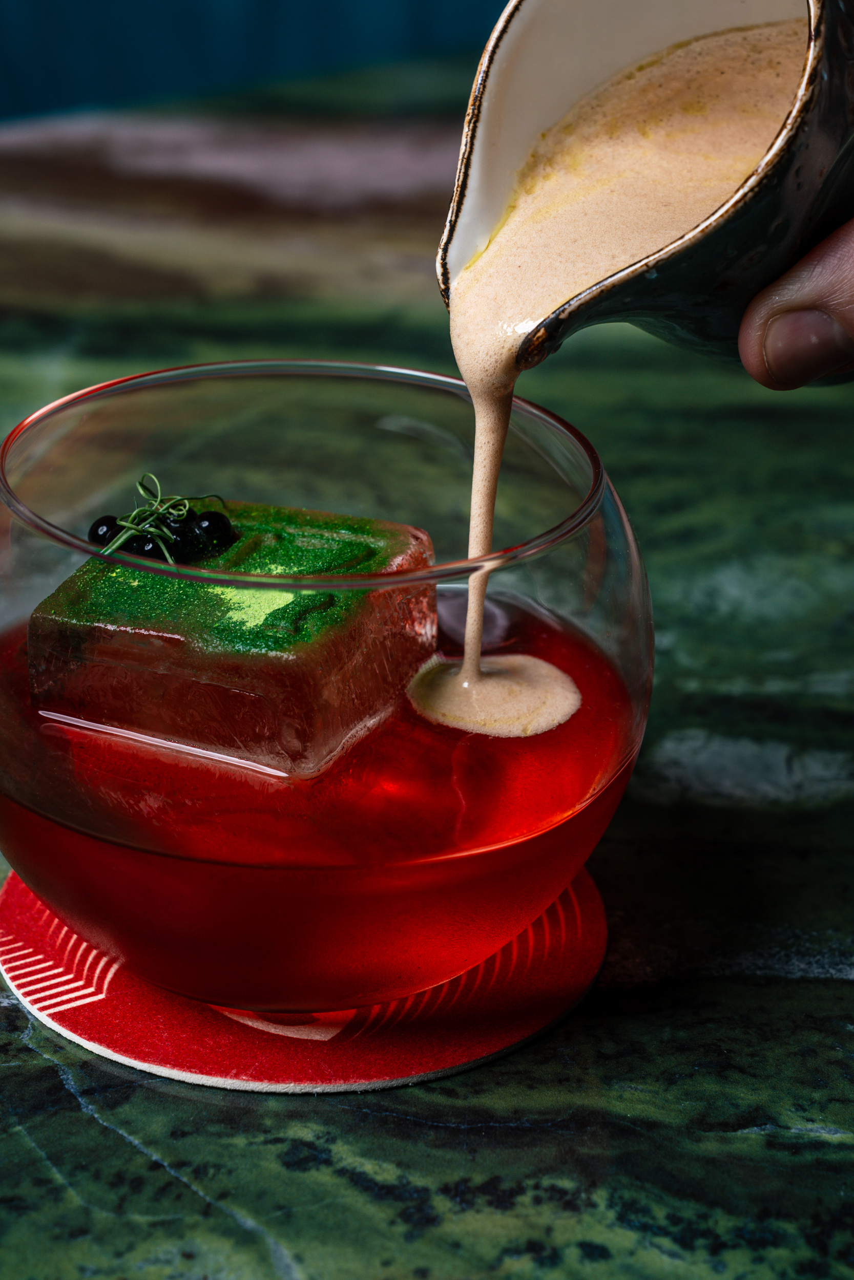 Nergroni Style Cocktail with champagne and balsamic foam poured over the ice cube