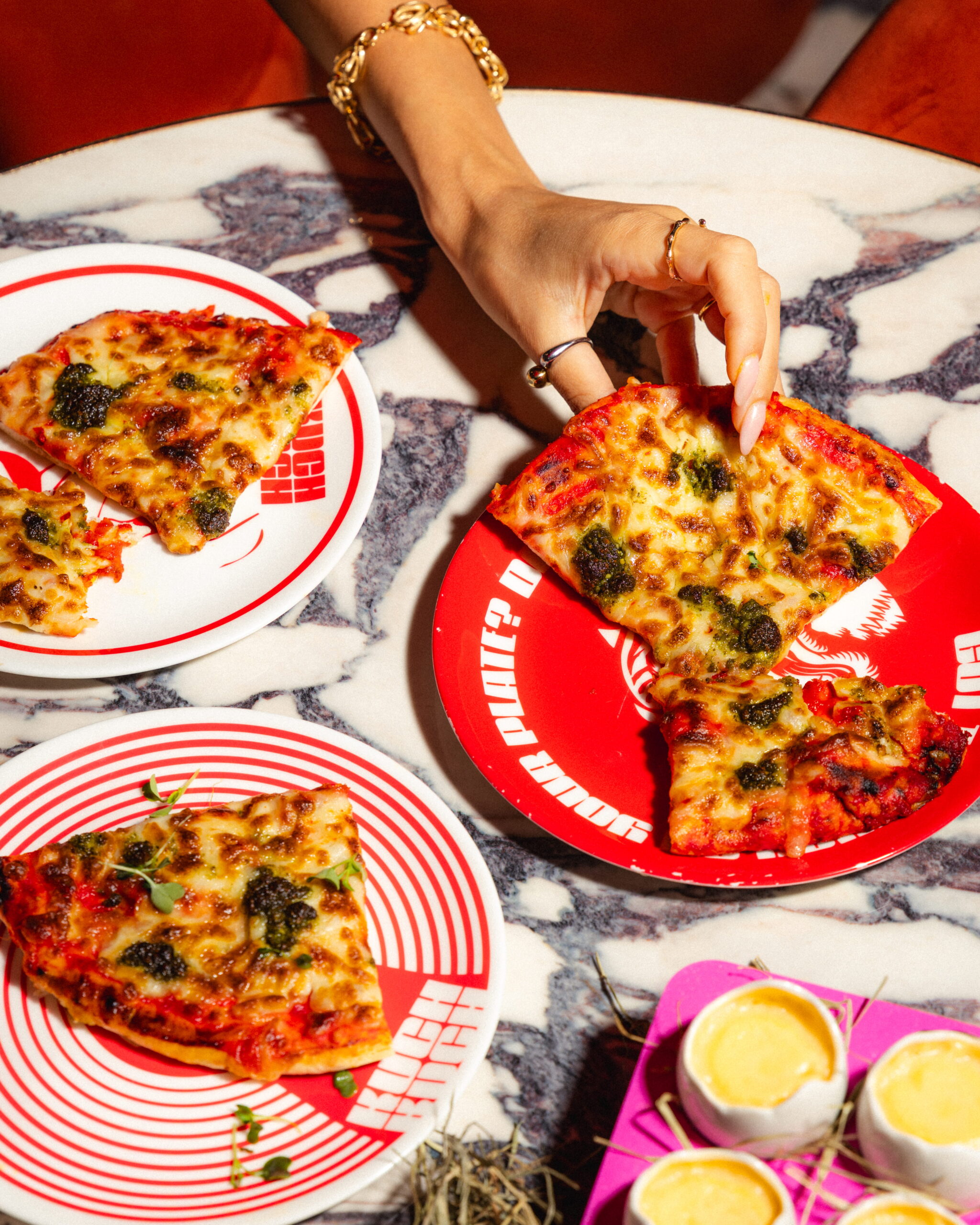 Kuch Kuch branded pizza slices and egg shell-style cocktail serves on a marble table at a creative cocktail bar in St Julian’s, Malta.
